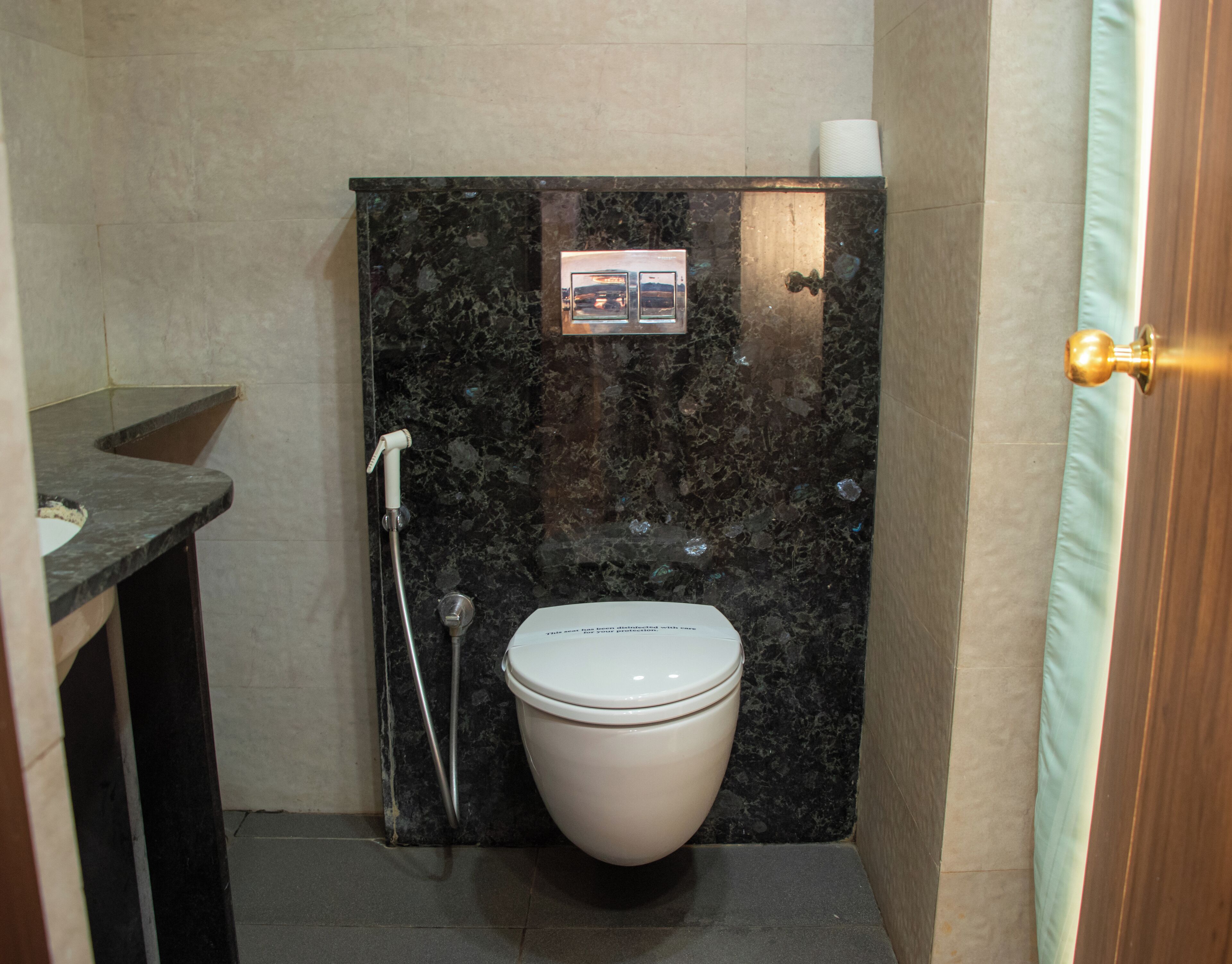Un baño pequeño con pared de mármol, inodoro blanco, ducha y un lavamanos.