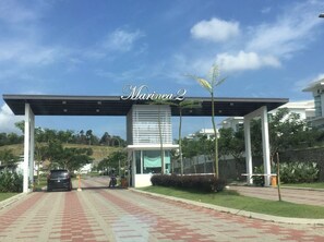 A modern building entrance with a covered walkway, a car, and a motorcycle.