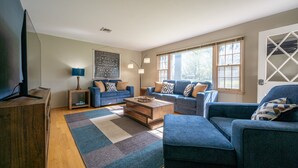 A modern living room with two sofas, a coffee table, and a TV on a wooden stand. - Grandma's House | Classic Indy Charm, Private Yard (Indianapolis)