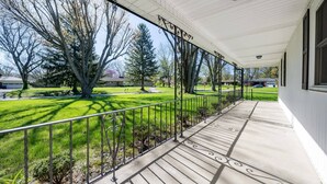 A covered porch with a metal railing, a concrete floor, and a view of a well-maintained lawn and trees. - Grandma's House | Classic Indy Charm, Private Yard (Indianapolis)