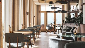 A modern restaurant with high ceilings, large windows, and a mix of wooden and upholstered furniture. - Blendin Bloemendaal (Overveen)