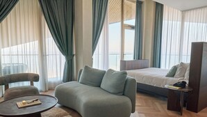 A modern hotel room with a large bed, a sofa, a round coffee table, and a small side table. - Blendin Bloemendaal (Overveen)
