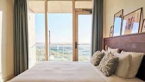 A hotel room with a large bed, a view of the landscape through a sliding door, and framed artwork on the wall. - Blendin Bloemendaal (Overveen)
