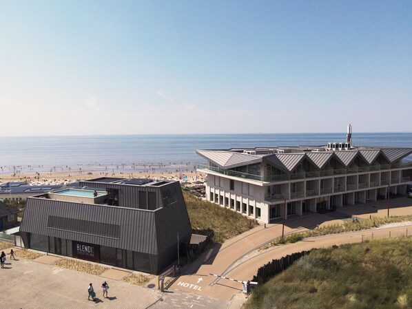 A modern hotel with a pool, located near a beach.