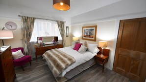 A bedroom with a bed, bedside tables, a chair, a dresser, a lamp, a mirror, a window with curtains, and a door. - Ladyland Cottage in Maybole (Maybole)