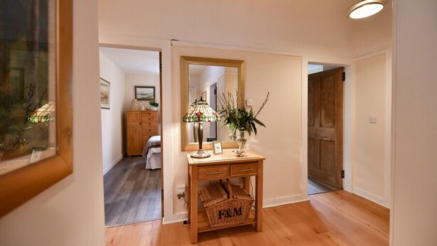 A hallway with a wooden console table, a mirror, and a basket labeled "F&M". - Ladyland Cottage in Maybole (Maybole)