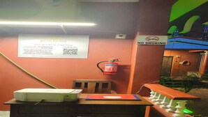 A room with a table, a chair, a fire extinguisher, a no smoking sign, and a signboard with text and QR code. - GoanFiesta Beach House Calangute (Calangute)