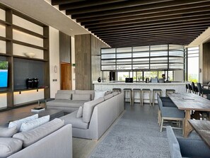 Relax and socialize in this stylish lounge area with a large sofa, bar stools, and a long dining table.