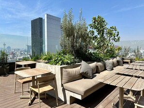 Relax and unwind on the rooftop terrace with a panoramic city view, surrounded by lush greenery and modern architecture.