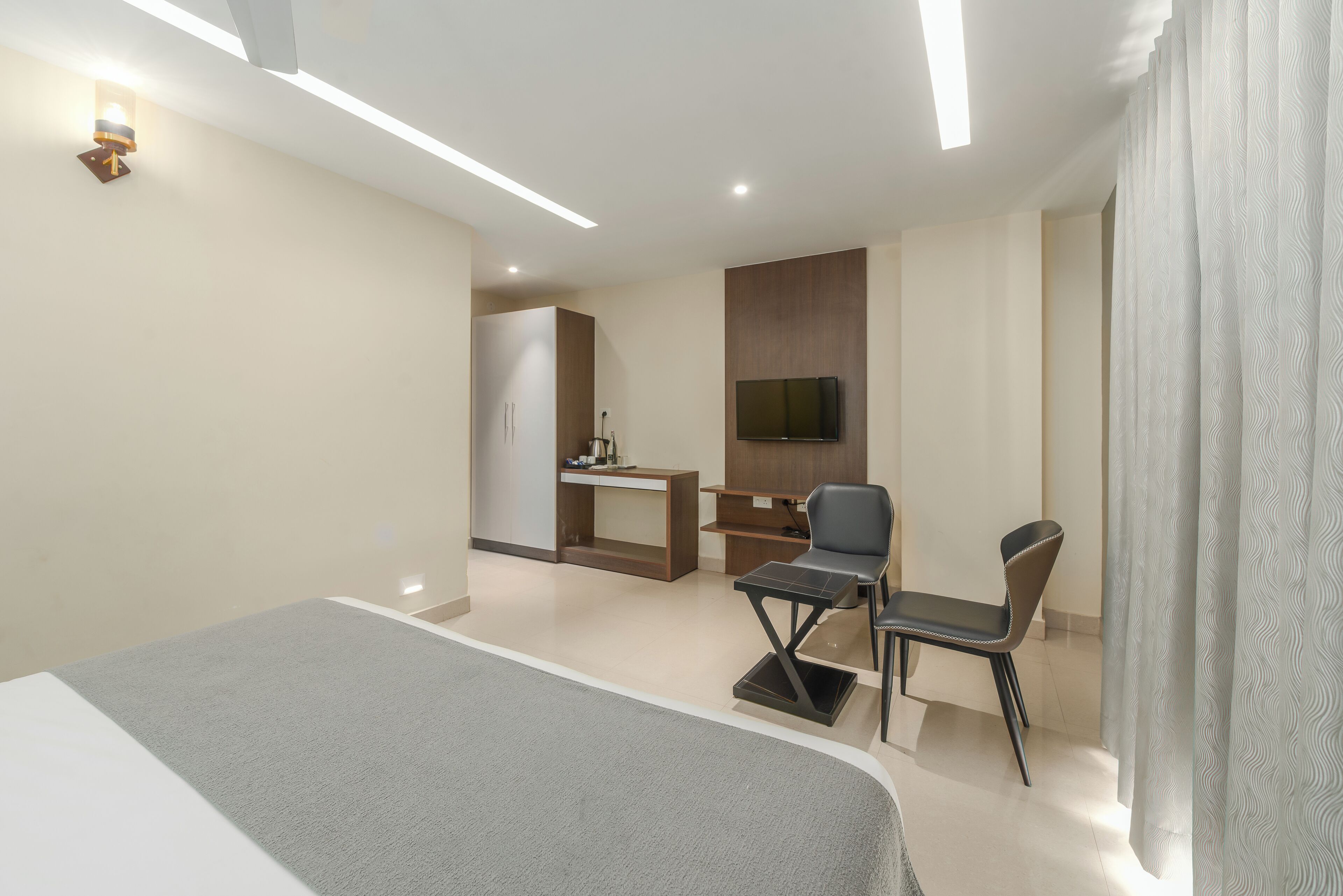 A hotel room with a bed, a desk, a chair, and a TV.