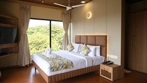 A modern hotel room with a large bed, a ceiling fan, a TV, and a view of the outdoors. - Hotel Shoolin Grand (Mangaluru)