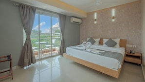 A modern hotel room with a large bed, a balcony with a table and chairs, and a view of the cityscape. - Hotel Shoolin Grand (Mangaluru)
