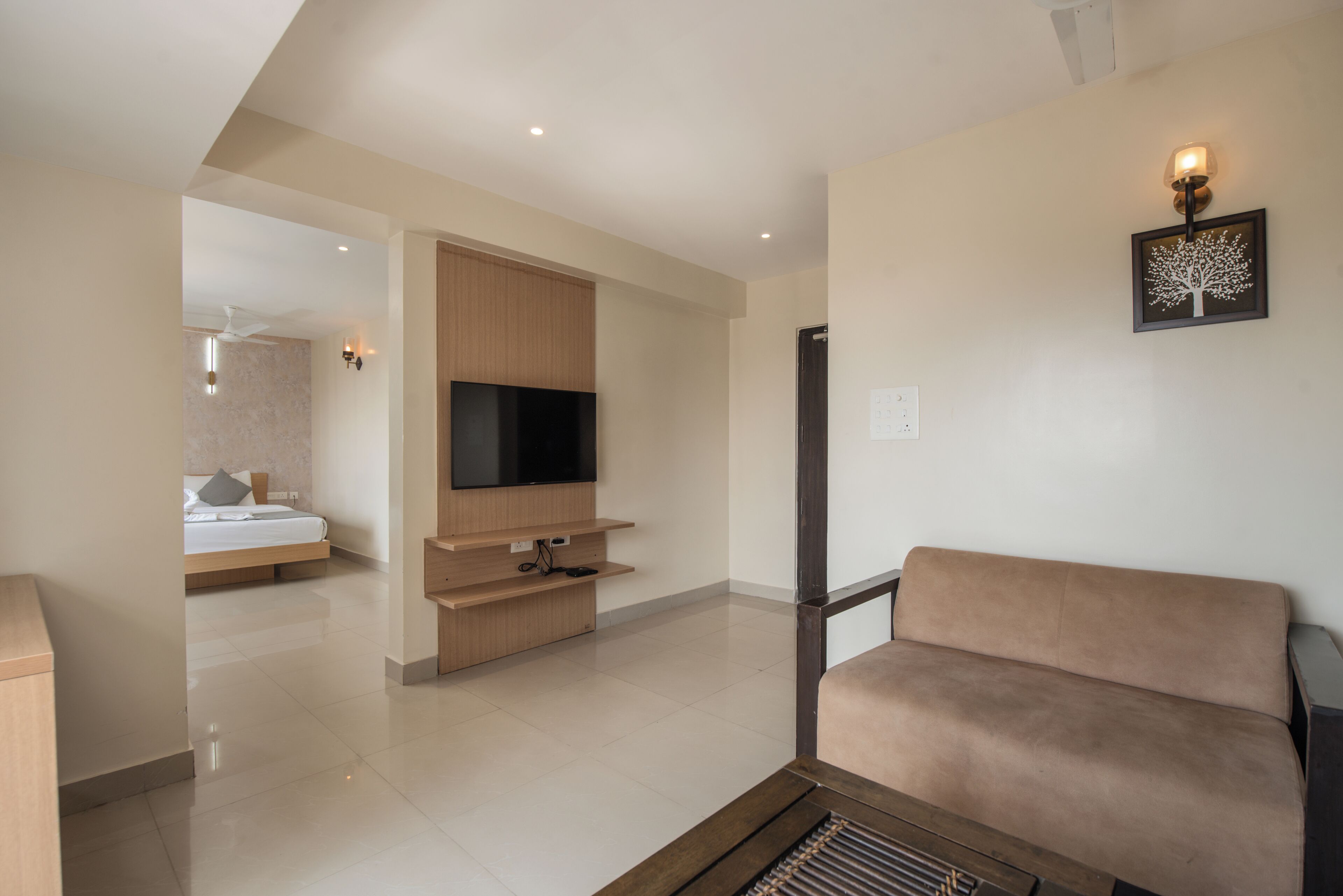 A modern living room with a flat-screen TV, a sofa, and a wooden entertainment unit.