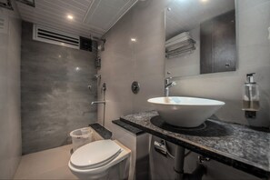 Un baño moderno con inodoro blanco, un lavamanos grande y una zona de ducha.