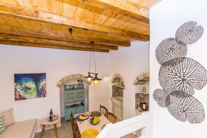 A dining area with a table set for two, a blue cabinet, and a painting on the wall. - Ep Avlis Apartments (Naxos)