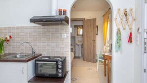 A compact kitchen with a toaster oven, a sink, and a tiled backsplash. - Ep Avlis Apartments (Naxos)