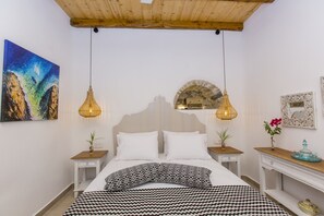 A bedroom with a bed, two bedside tables, a nightstand, a wall-mounted mirror, a painting, and two hanging lamps. - Ep Avlis Apartments (Naxos)