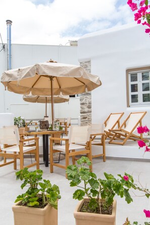 An outdoor seating area with a table, chairs, and a large umbrella. - Ep Avlis Apartments (Naxos)