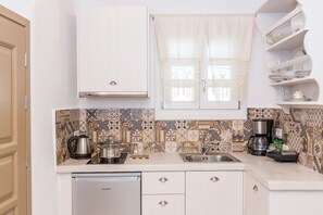 A kitchen with white cabinets, a coffee maker, a kettle, and a dishwasher. - Ep Avlis Apartments (Naxos)
