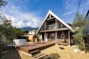 Ein modernes Haus mit einer Holterrasse, einem Whirlpool und einem Schaukelstuhl.