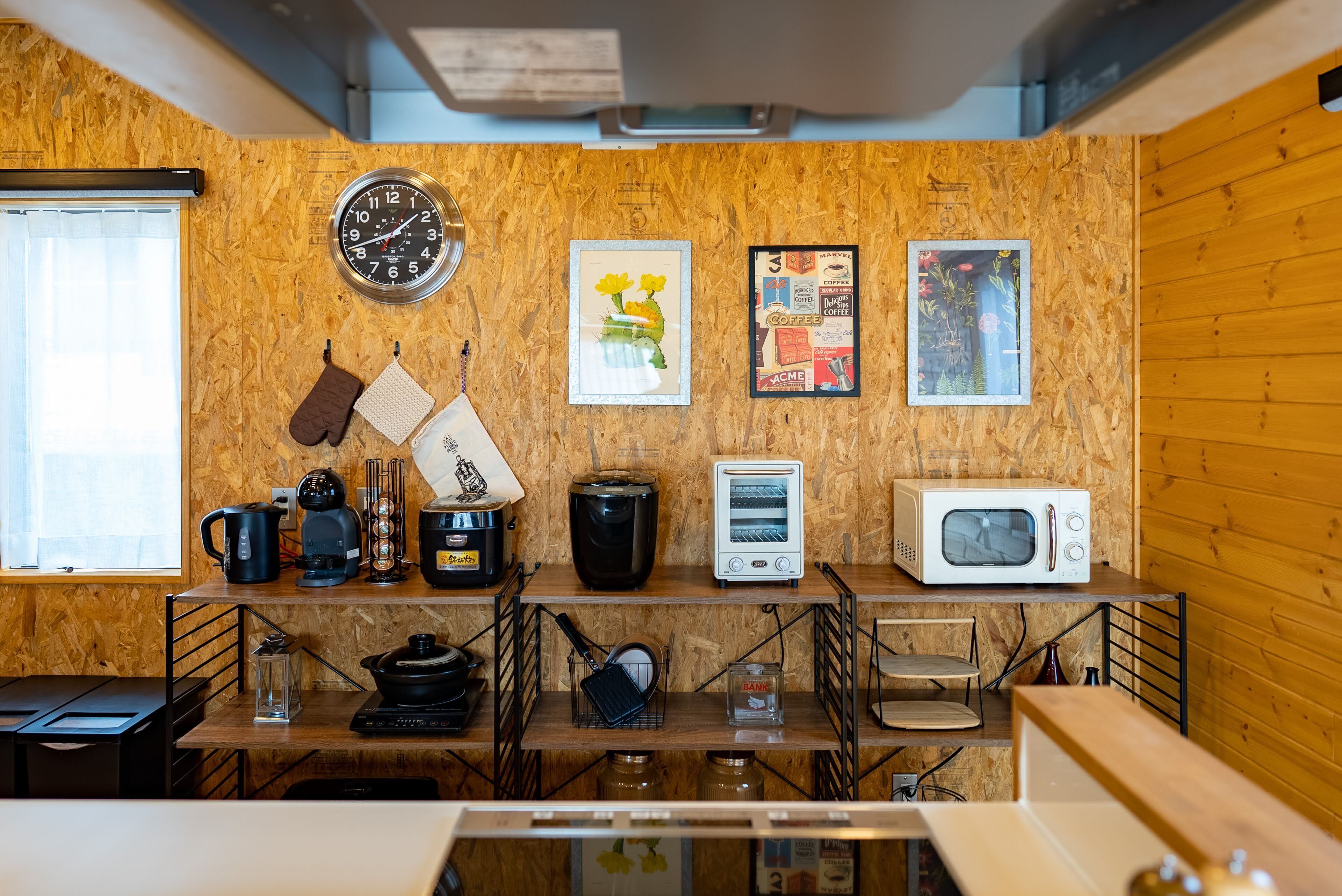 Une cuisine avec des murs en bois, une horloge et divers appareils électroménagers.