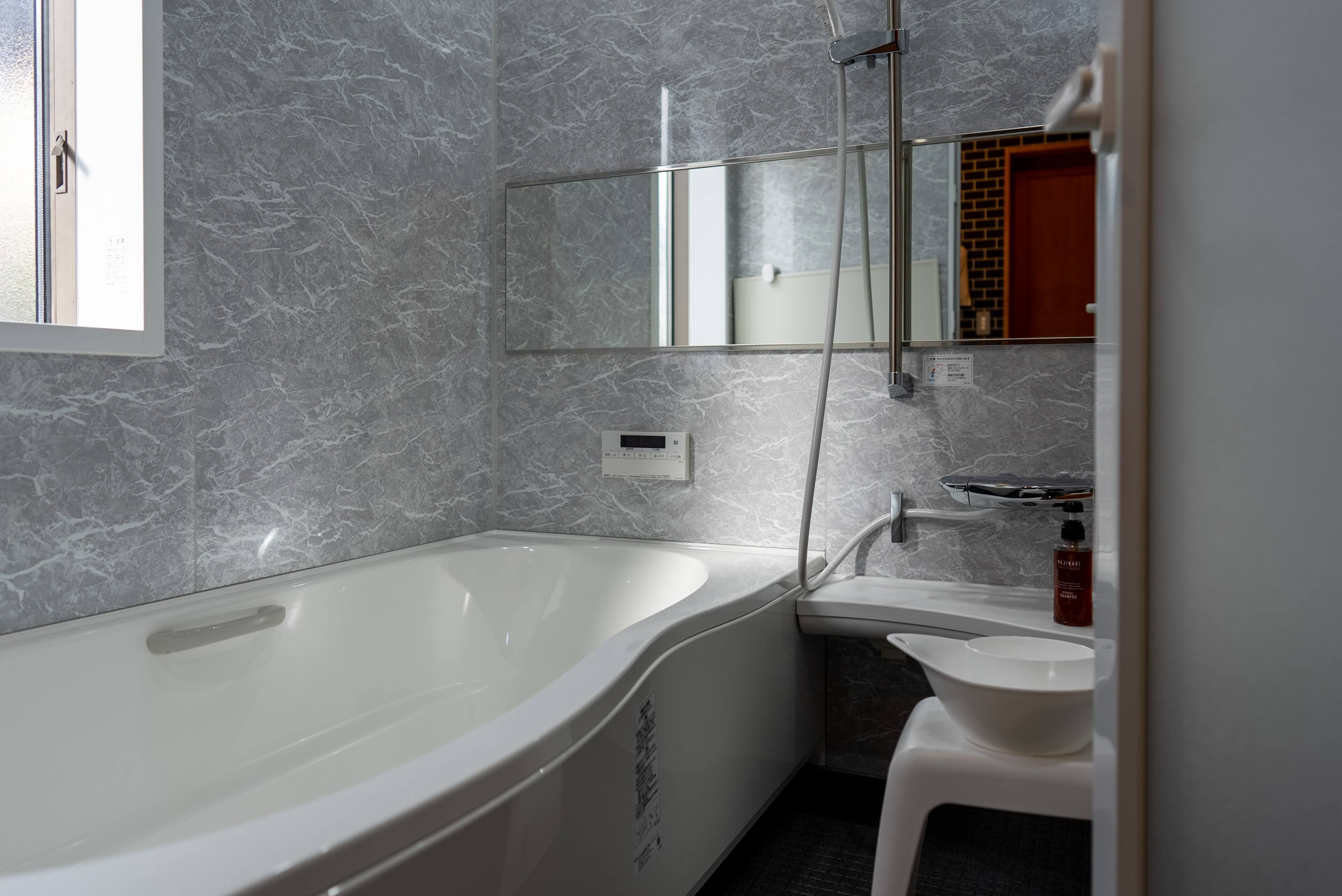A modern bathroom with a freestanding bathtub, a mirror, a sink, and a toilet.