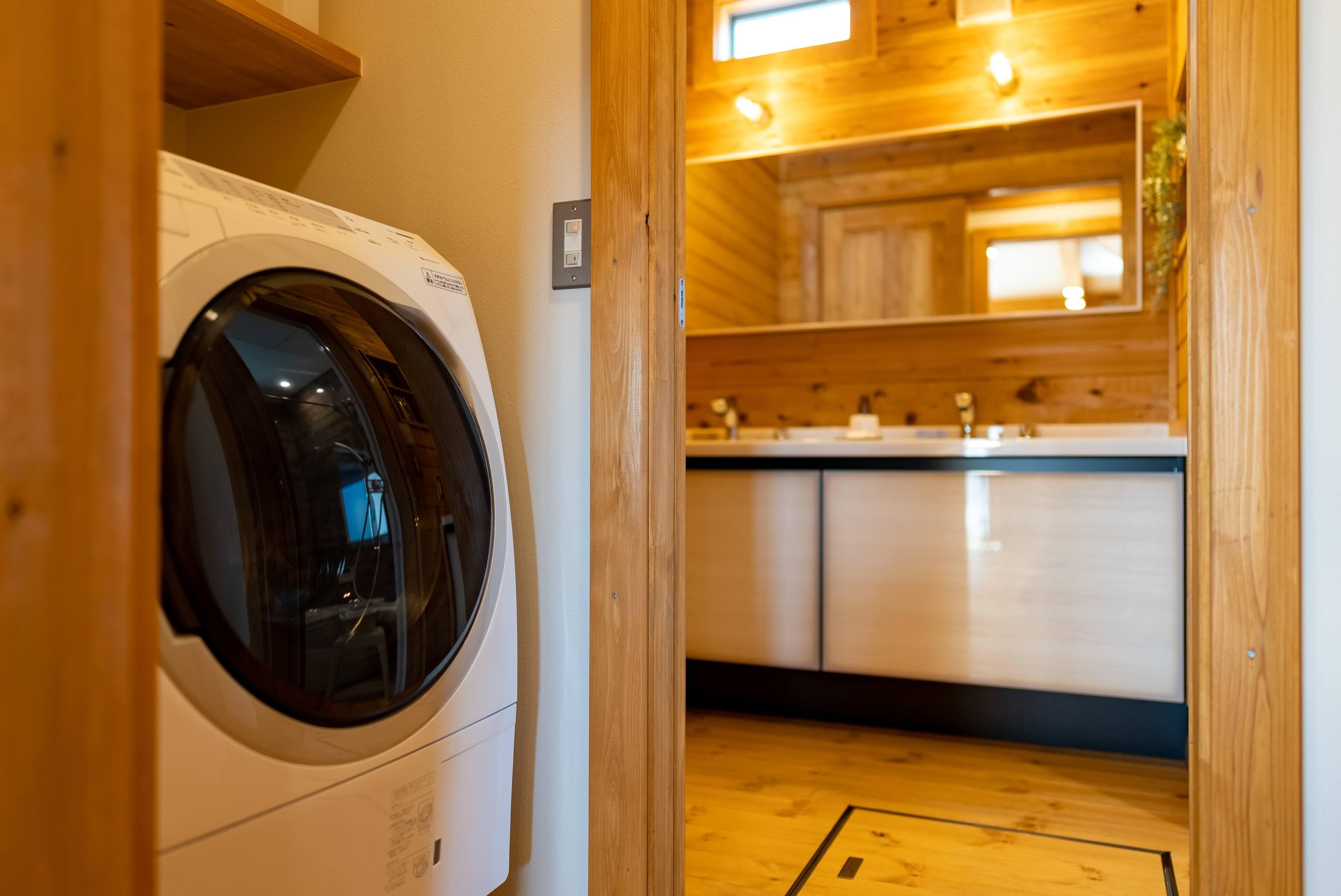 A laundry room with a front-loading washing machine, wooden cabinets, and a sink.