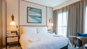 A hotel room with a large bed, two bedside tables, a desk, a chair, and a view of the outdoors. - Zapbed House - ADP 2108 (Dubai)