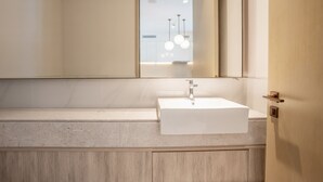 A modern bathroom with a white sink, a large mirror, and a wooden vanity. - Zapbed House - ADP 2108 (Dubai)