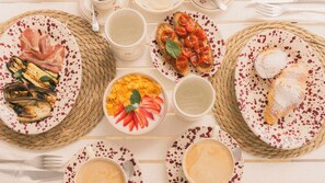 A table set with various dishes, including grilled vegetables, a fruit salad, and pastries, suggesting a meal setting. - Tenuta Doxi (Sannicola)
