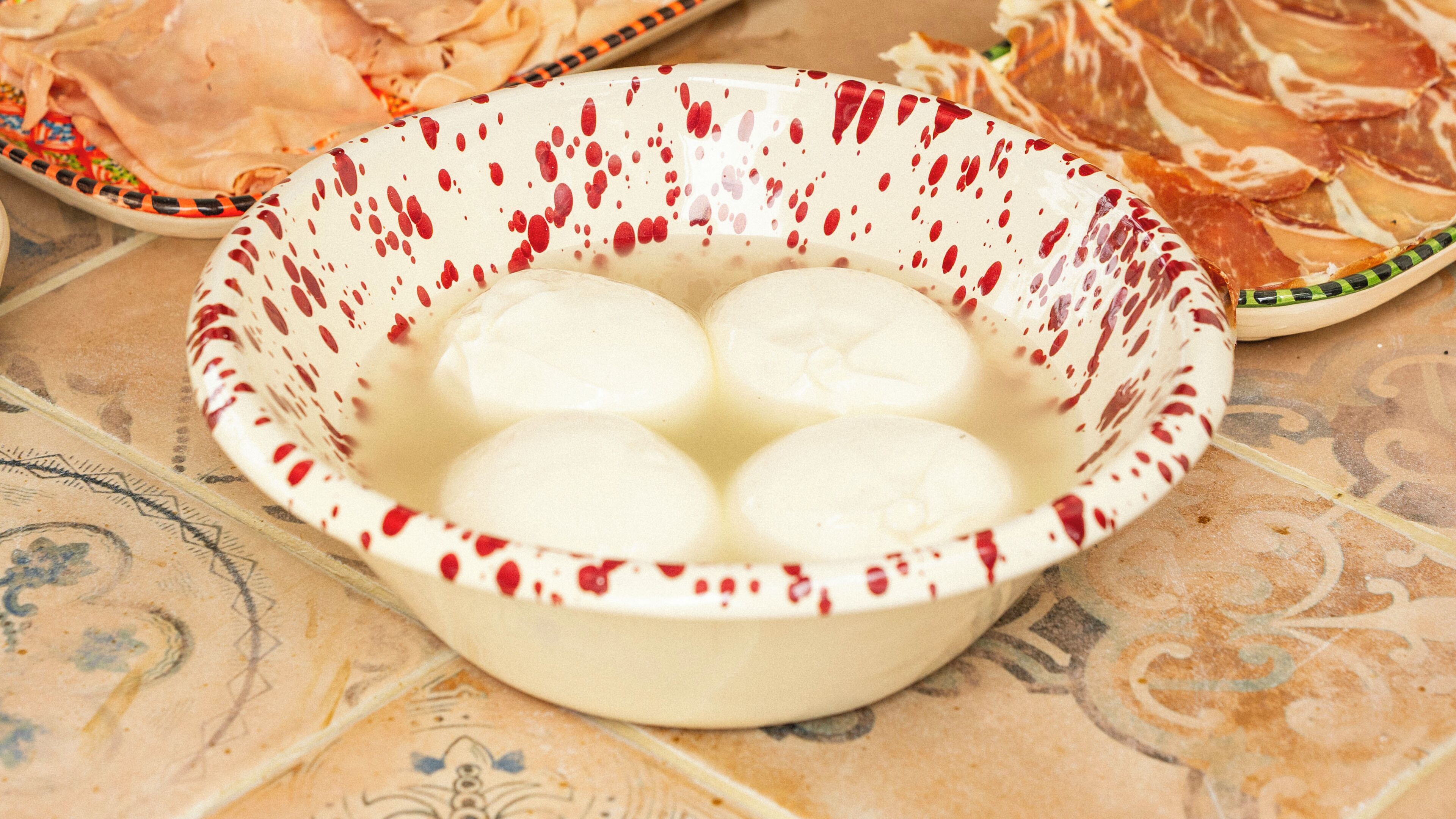 Uma tigela com quatro bolas brancas sobre uma toalha de mesa estampada.