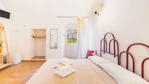 Quarto com cama, mesa de cabeceira, espelho, guarda-roupa e chuveiro.