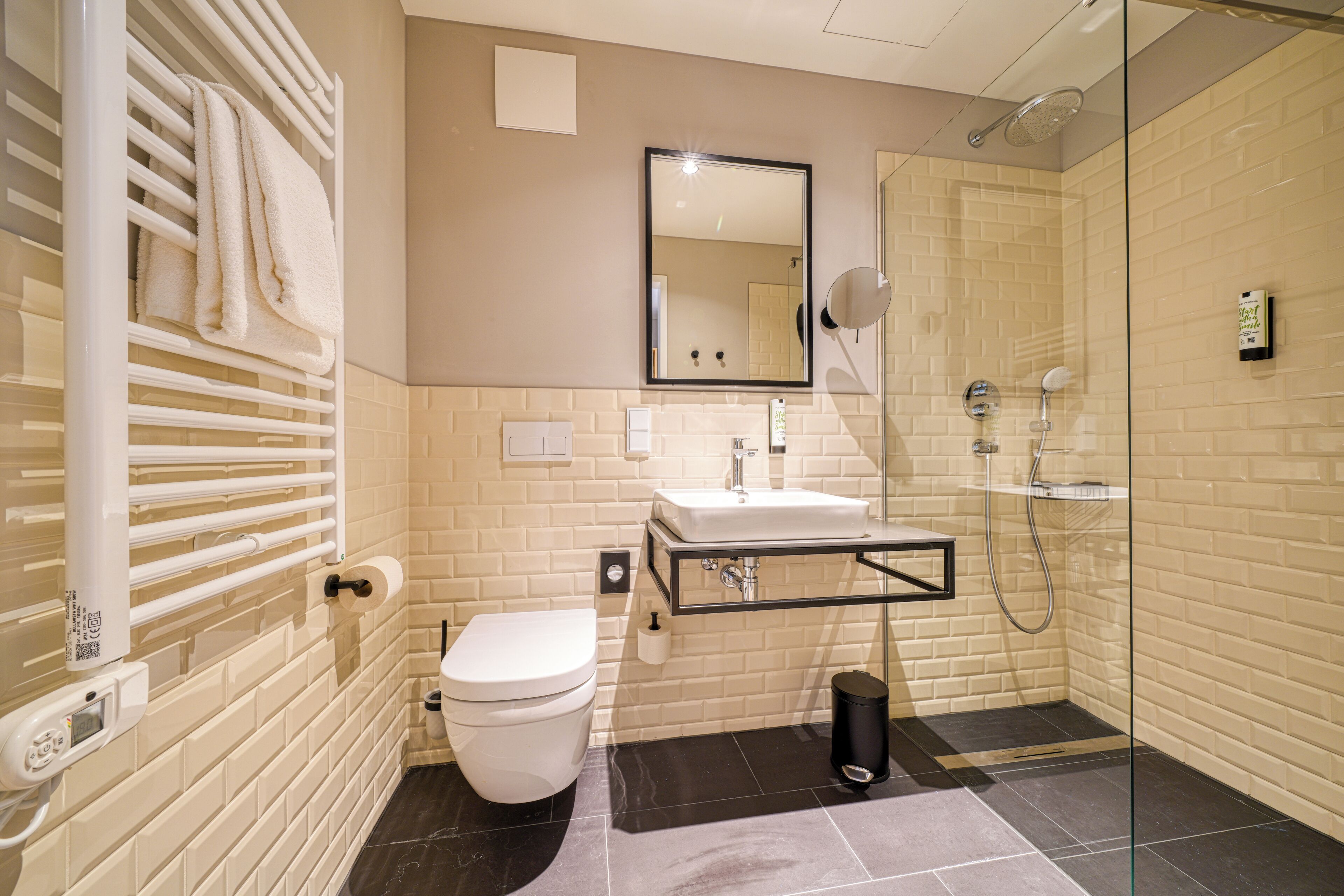 Un baño moderno con inodoro, lavamanos y ducha con mampara de vidrio.