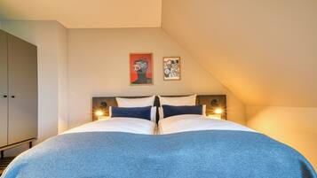 Ein Schlafzimmer mit einem großen Bett, zwei Wandleuchten und zwei gerahmten Kunstwerken an der Wand.