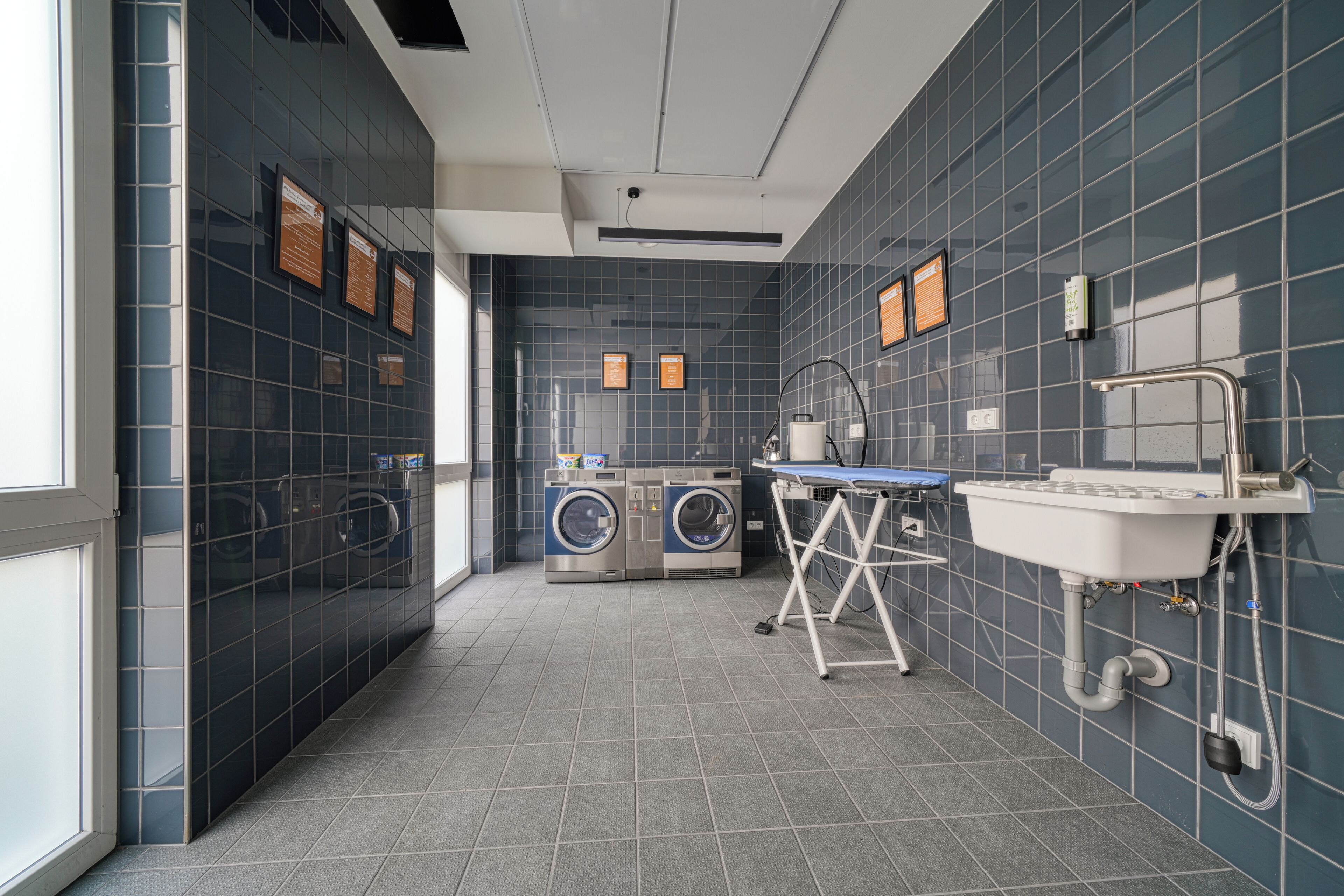Un baño moderno con un espejo grande, un lavamanos y dos lavadoras.