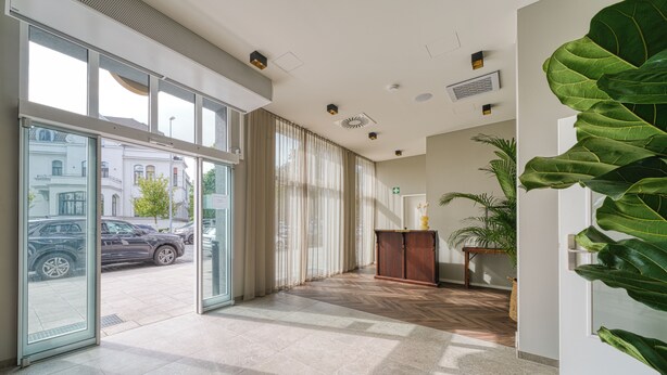Eine geräumige Lobby mit großen Fenstern, Holzboden und einer Rezeption.