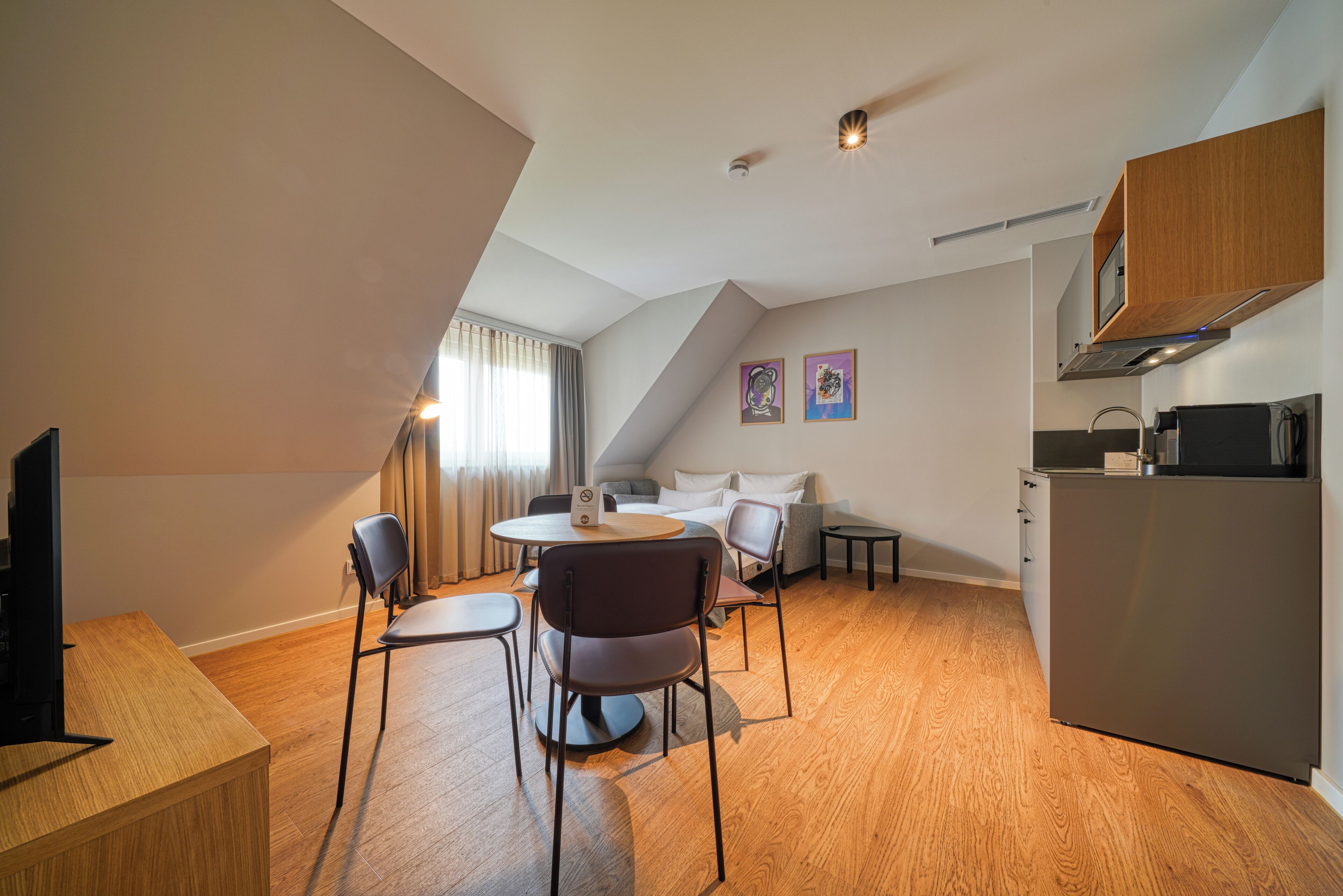 Un espacio habitable moderno y compacto con comedor, kitchenette y una zona de estar acogedora.