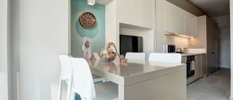A modern kitchen with white cabinetry, a central island, and a teal accent wall.