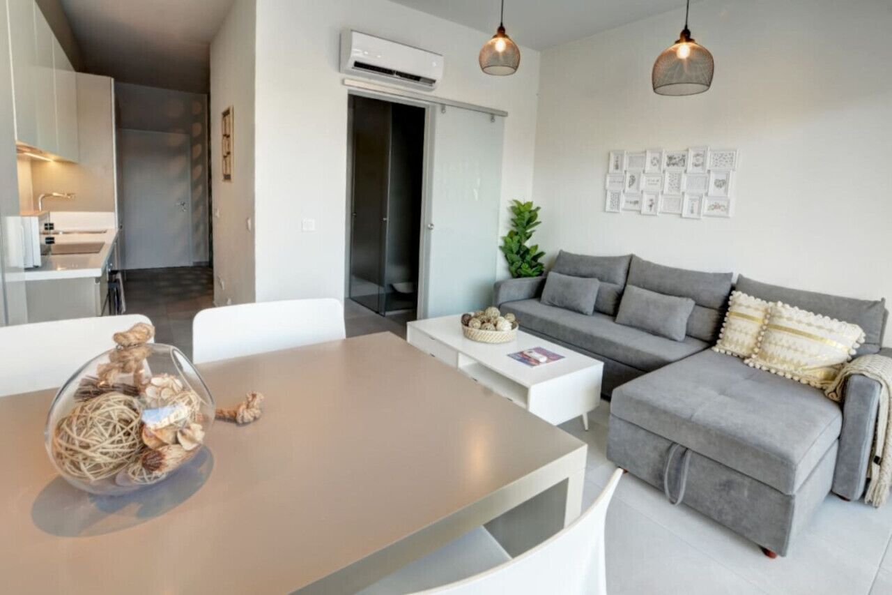 Ein modernes Wohnzimmer mit einem grauen Sofa, einem Couchtisch und einem Esstisch.
