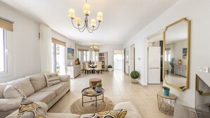 A spacious living area with a sofa, coffee table, and a dining area in the background. - SunnyVillas: 3BR Family Villa☆Private Pool (Protaras)