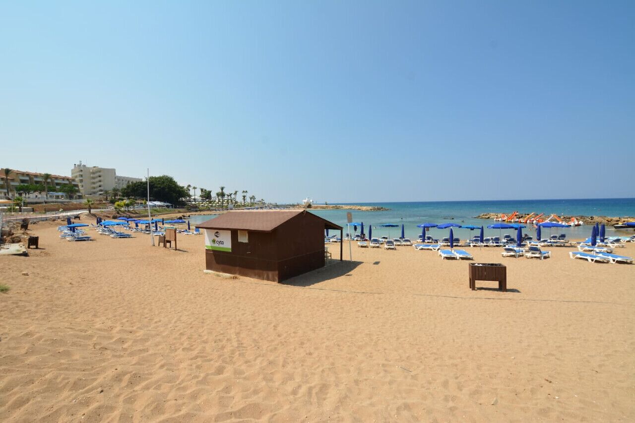A beach with a small wooden hut, sun loungers, and umbrellas.