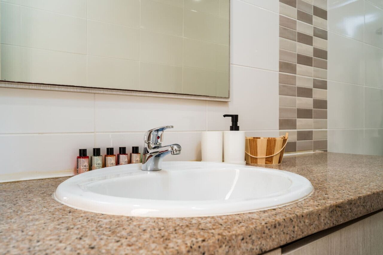 Een badkamer met een witte wastafel, een spiegel en toiletartikelen op het aanrecht.