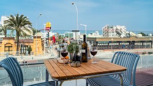 Una terraza en la azotea con una mesa de madera, dos sillas y una botella de vino.