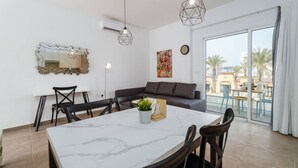 A modern living room with a dining area, a large window with a view, and a painting on the wall.