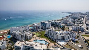 A coastal hotel with multiple buildings, a swimming pool, and a view of the ocean.
