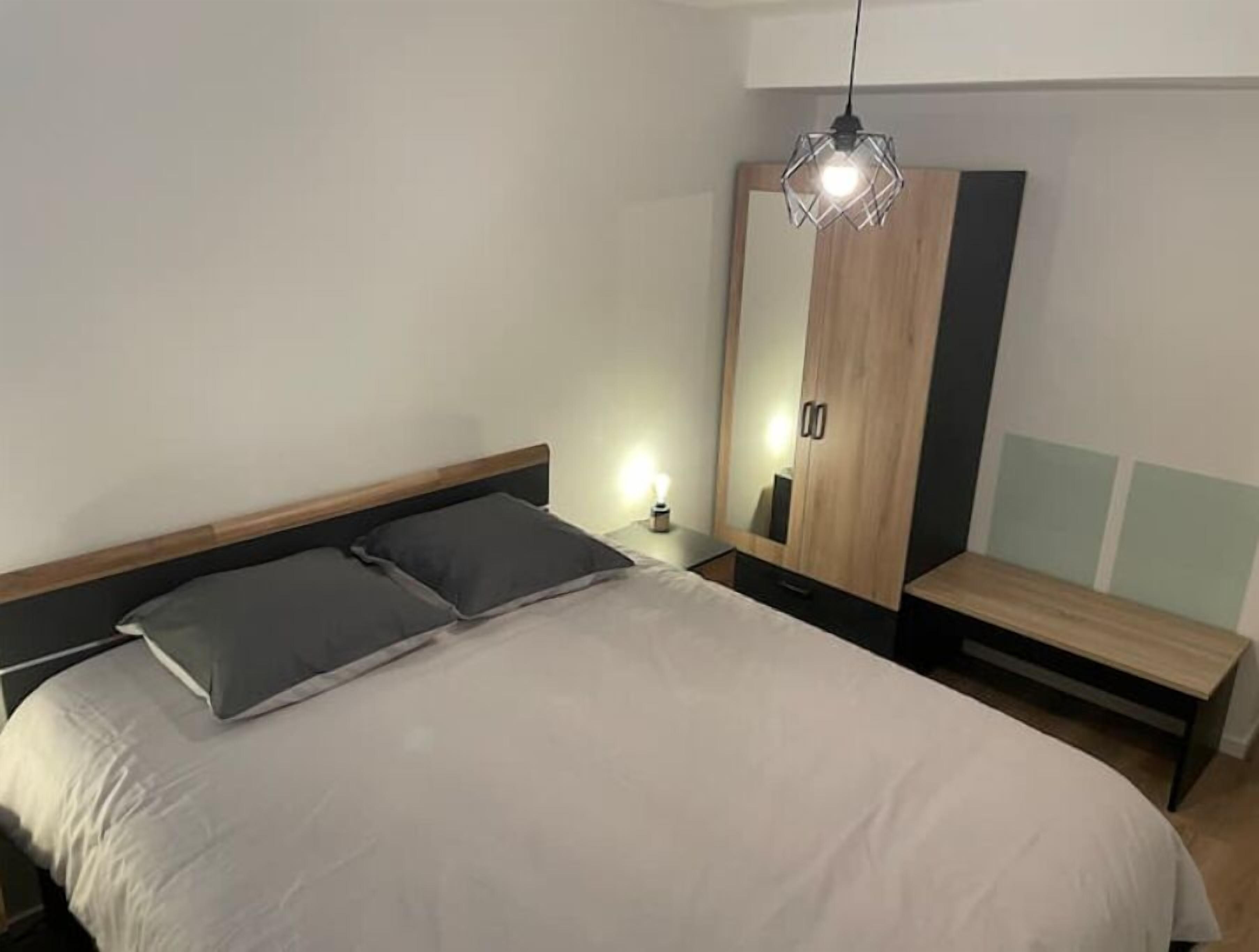 A modern bedroom with a bed, bedside table, and a wardrobe.