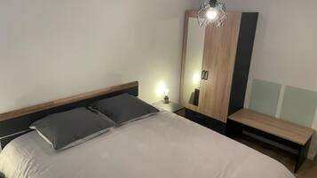 A modern bedroom with a bed, bedside table, and a wardrobe.