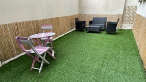 A small patio area with artificial grass, a table, and two chairs. - Appartement Avec Terrasse Proche de Paris et La Défense (Puteaux)