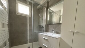 A bathroom with a shower, a sink, and a mirror. - Appartement Avec Terrasse Proche de Paris et La Défense (Puteaux)