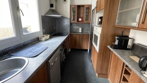 A compact kitchen with a sink, stove, and cabinets. - Appartement Avec Terrasse Proche de Paris et La Défense (Puteaux)